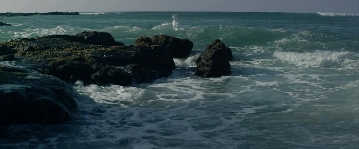 The waves splash against the rocks