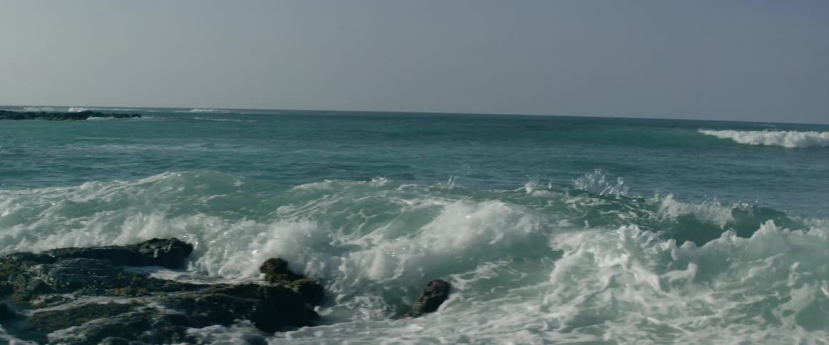 The large waves splash over the rocks