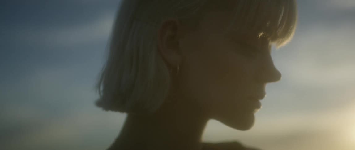 A woman stands outside at sunset