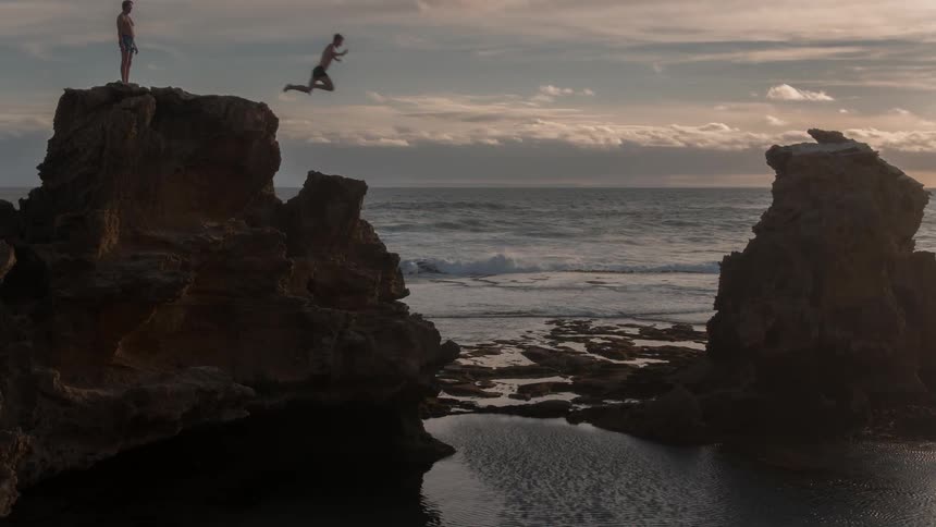 A man dives off the cliff into the water
