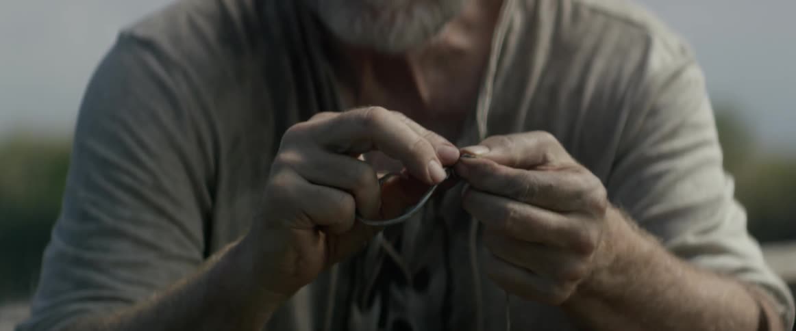 Bearded man outside tying string onto fishing hook