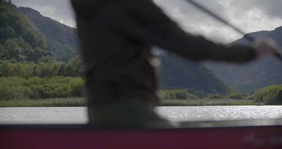 A man paddles a canoe on a mountain lake