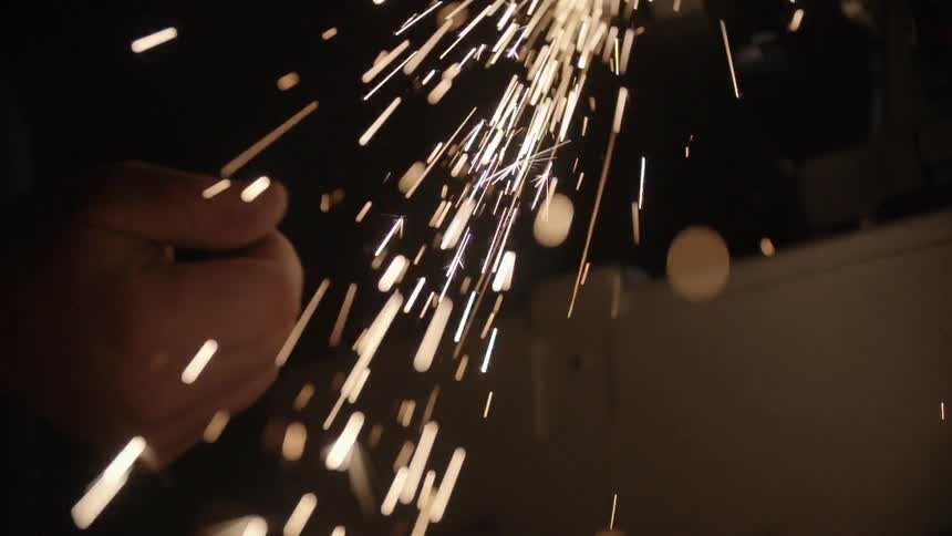 A hand catching sparks in a dark setting