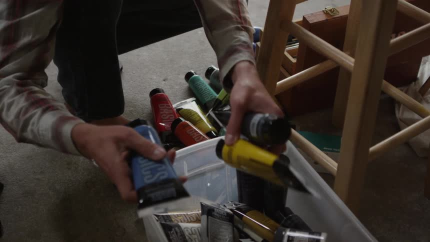 A man removes acrylic paint from a bin