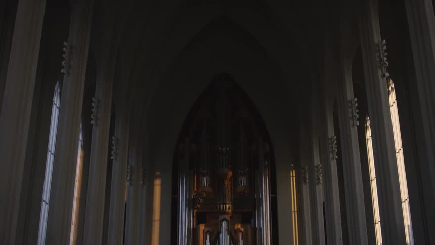 A cathedral room with arched windows and a large pipe organ