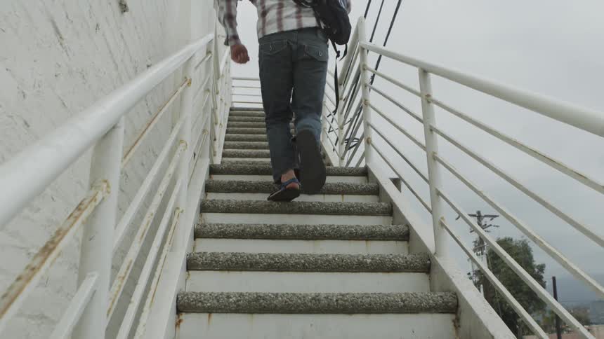 Man carrying a backpack runs up a flight of stairs