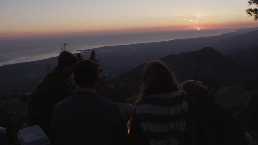 Friends are watching the sunset over a mountain