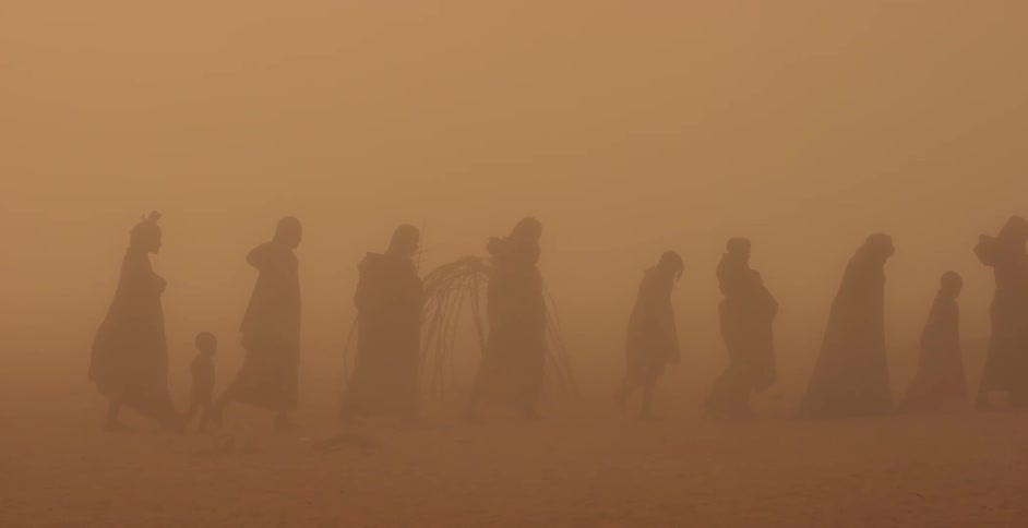 People walk through a sandstorm in the desert