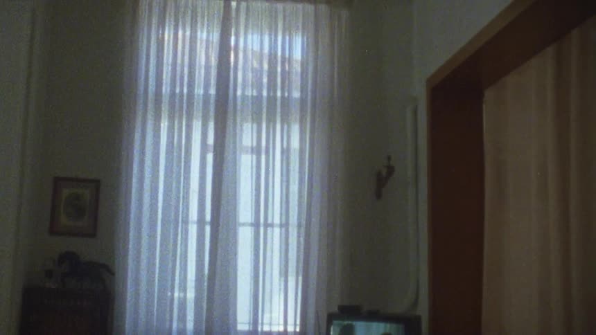 A small tv is playing in a room next to a window