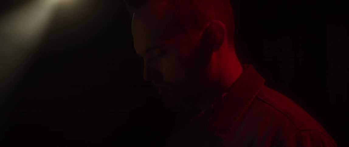 A light flashes behind a man's head in the dark