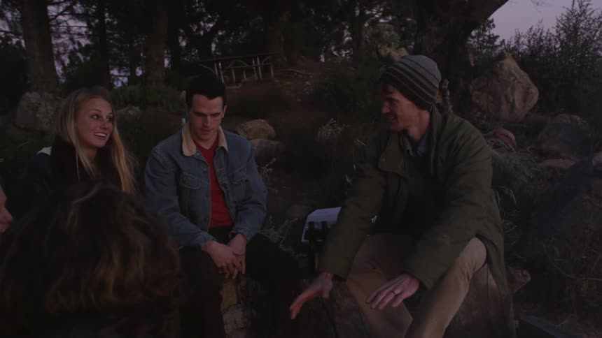 A group of friends sit around the campfire