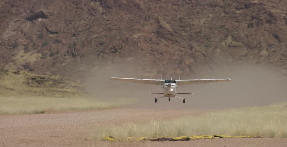 A small airplane takes off from a dirt road