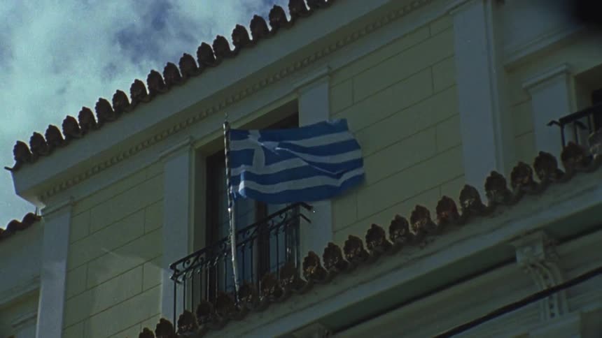 A greek flag on a window balcony is flapping in the breeze
