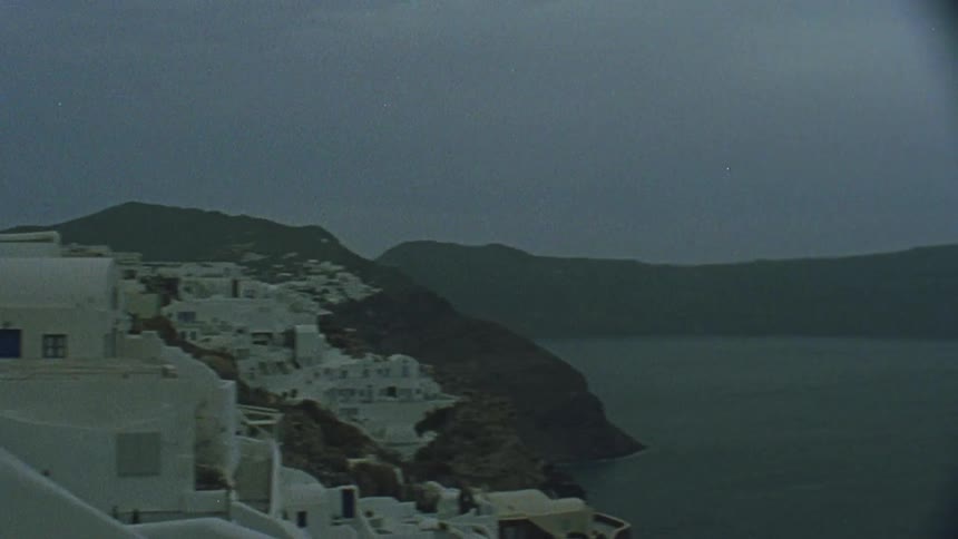 A village of white buildings clings to coastal hillsides
