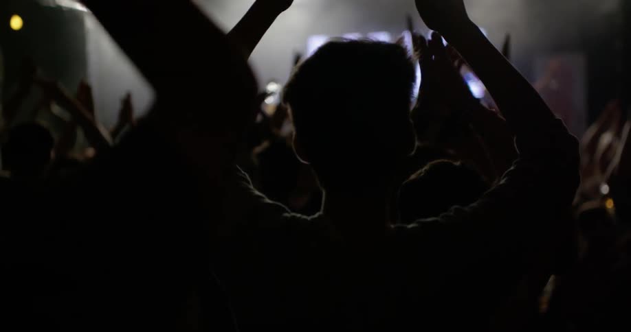 People dance and clap in a dance club