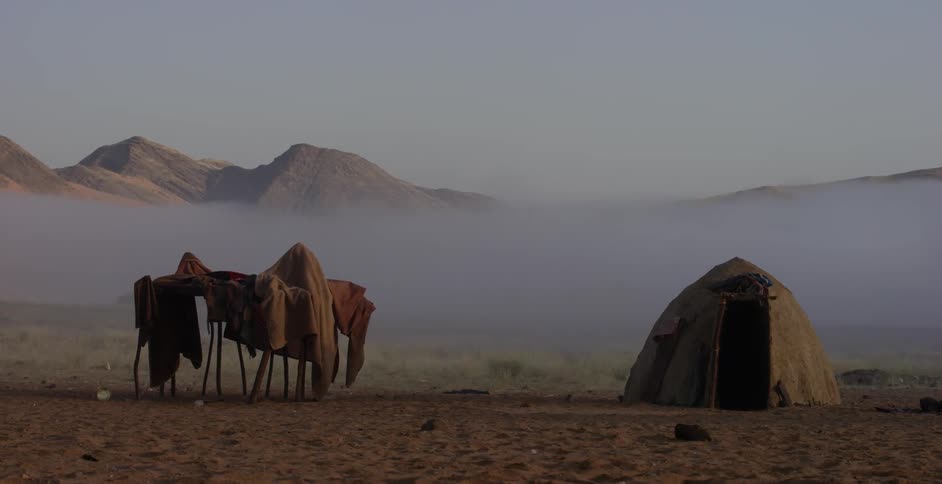 A tent is set up in a field by mountains