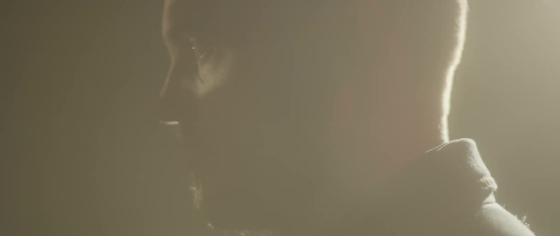 A man stares out intently as lights strobe around him