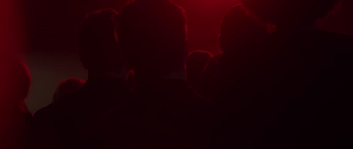 A crowd stands while colored lights flash
