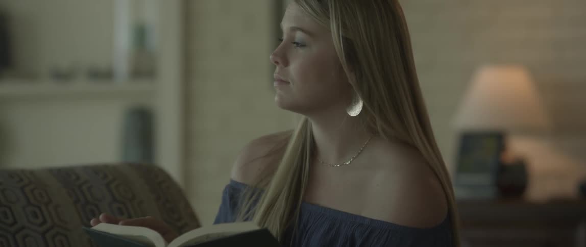 A woman stops to think while reading a book