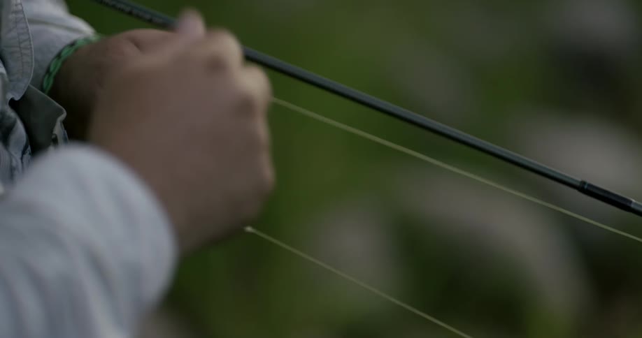 A fisherman pulls fishing line and ties it