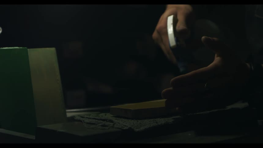 A worker uses a spray bottle on a piece of wood