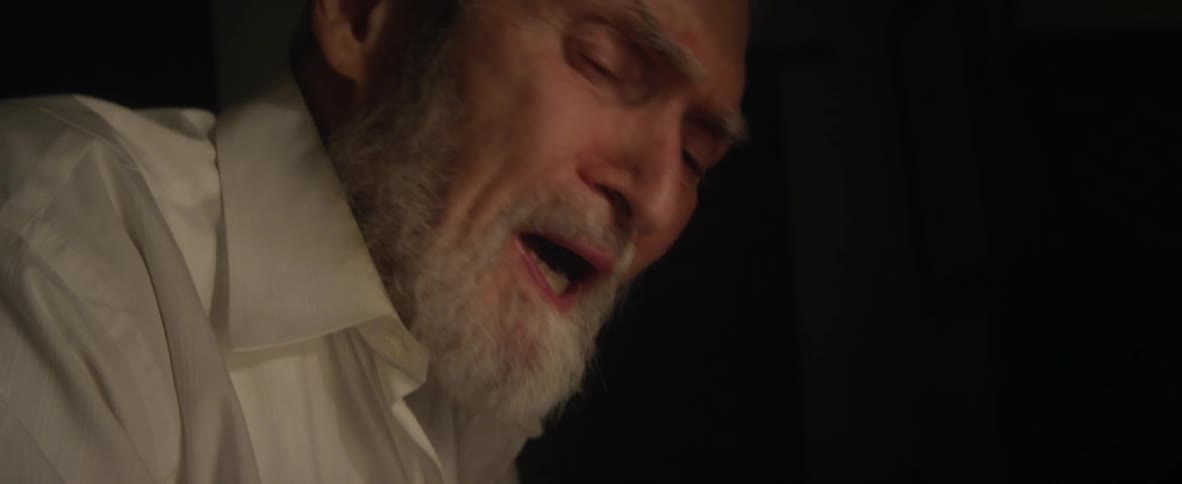 An elderly man walks disheveled in a house
