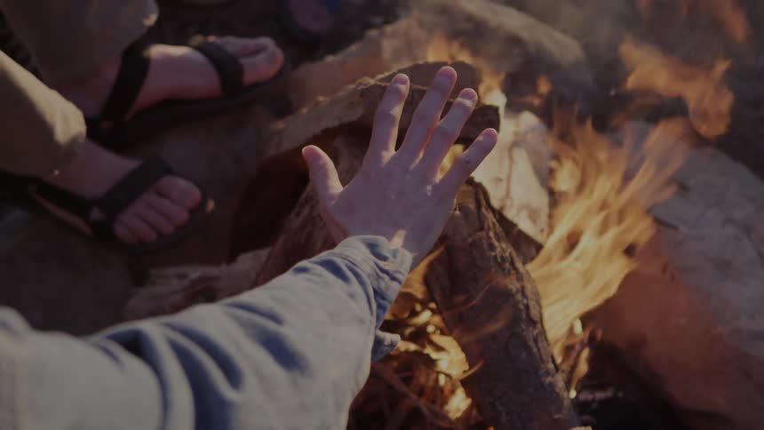 A person warms their hands by a fire