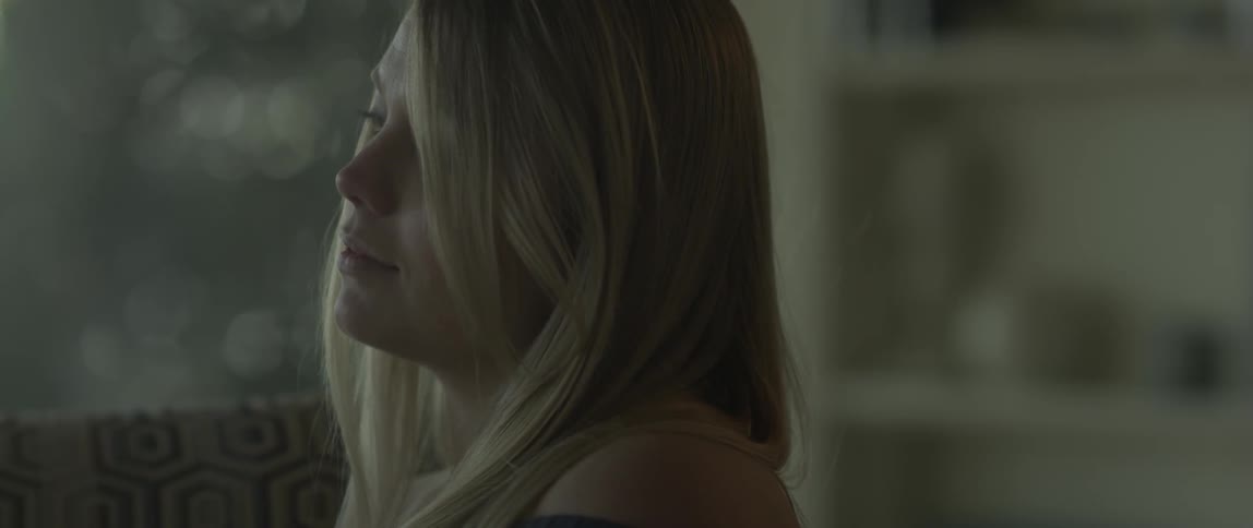 A blonde haired woman brushes her hair to the side