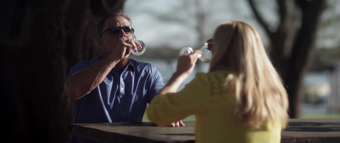 A man and a woman are sitting and having some wine together outside