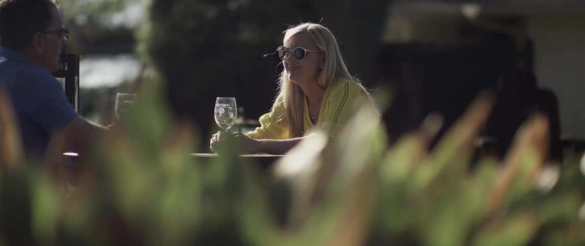 A woman and man are sitting outdoors at a table drinking wine