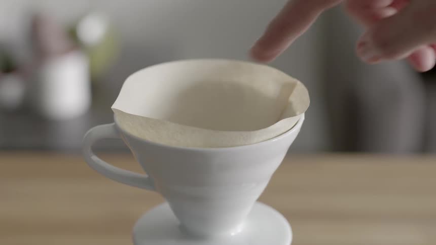 A person placing a parchment paper inside a cup