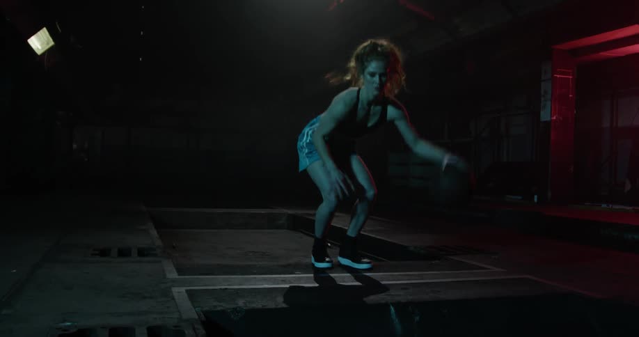 A woman is playing basketball in a dark alley
