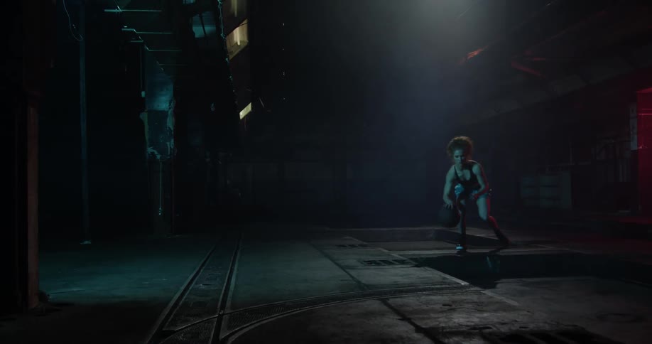 A woman dribbles the ball in the dark gym