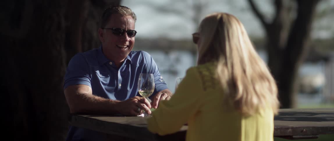 A man and woman converse outdoors while smiling