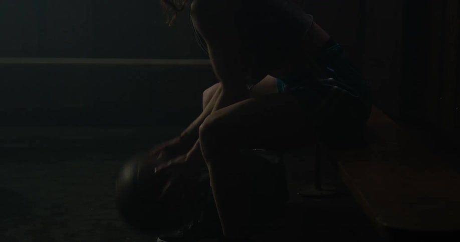 A woman dribbles a basketball while sitting on a bench