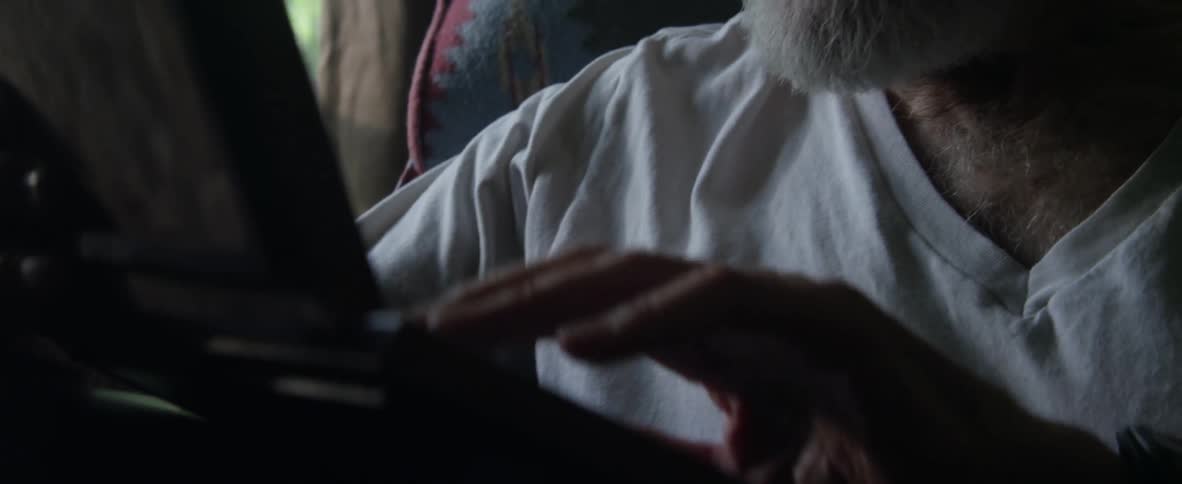 An elderly man types on a laptop