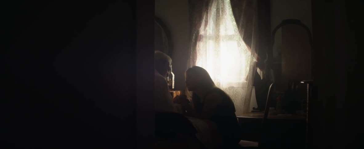 A man and women are sitting in the bedroom talking
