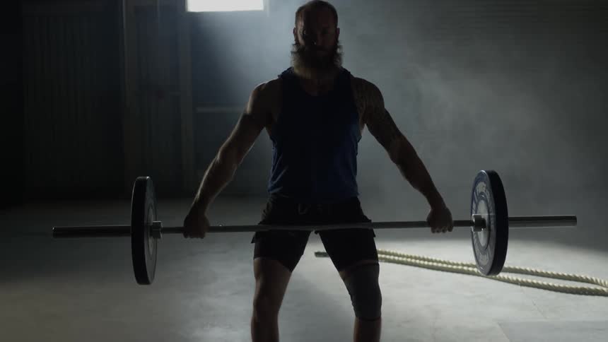 A man with a beard doing a squat press
