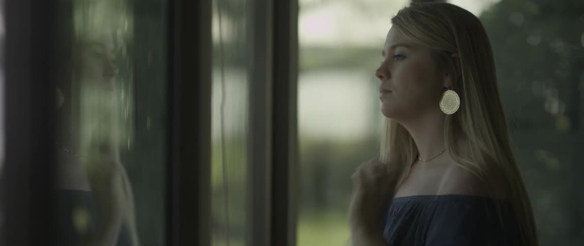A woman walks over and looks out the window