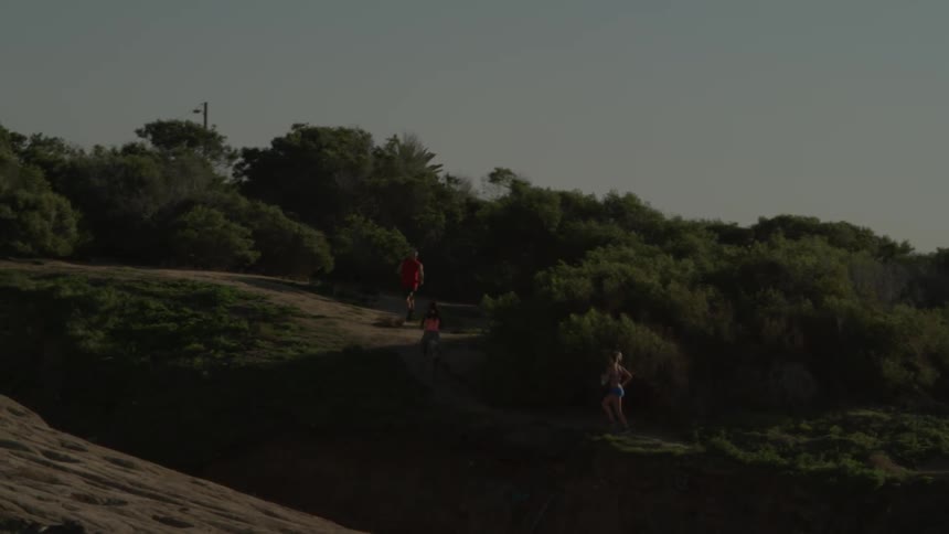 Three people run up a dirt trail