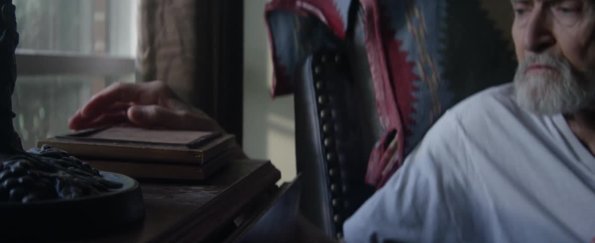 An elderly man reaches out and picks up a framed picture