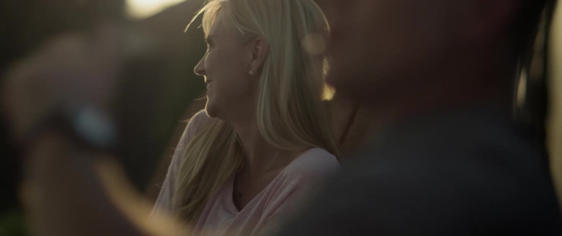 A man and woman converse outdoors smiling