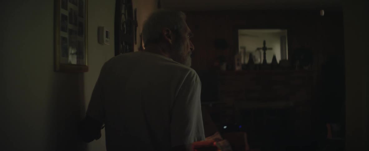 An elderly man walks into a living room