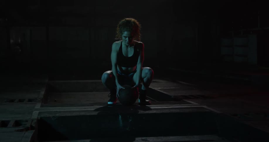 A woman kneels and leans on a basketball