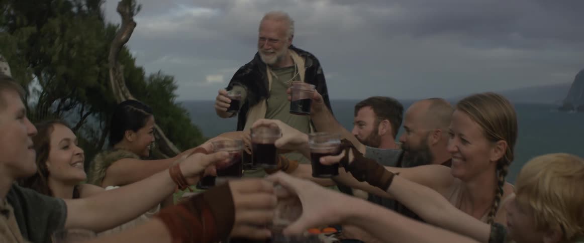 A man standing at the head of an outdoor table gives a toast