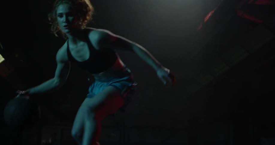 A woman dribbles a basketball between her legs