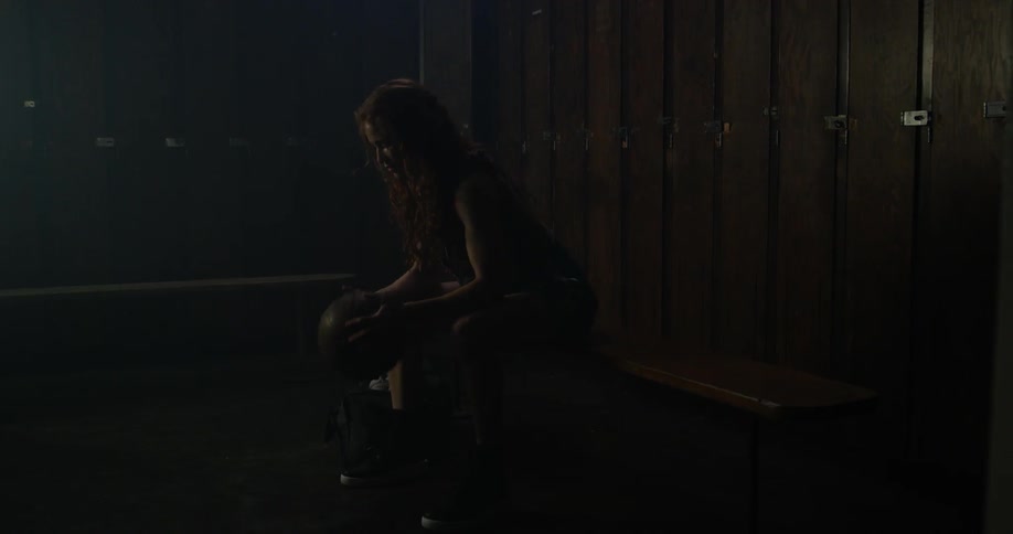 A woman sits on a bench gripping a basketball