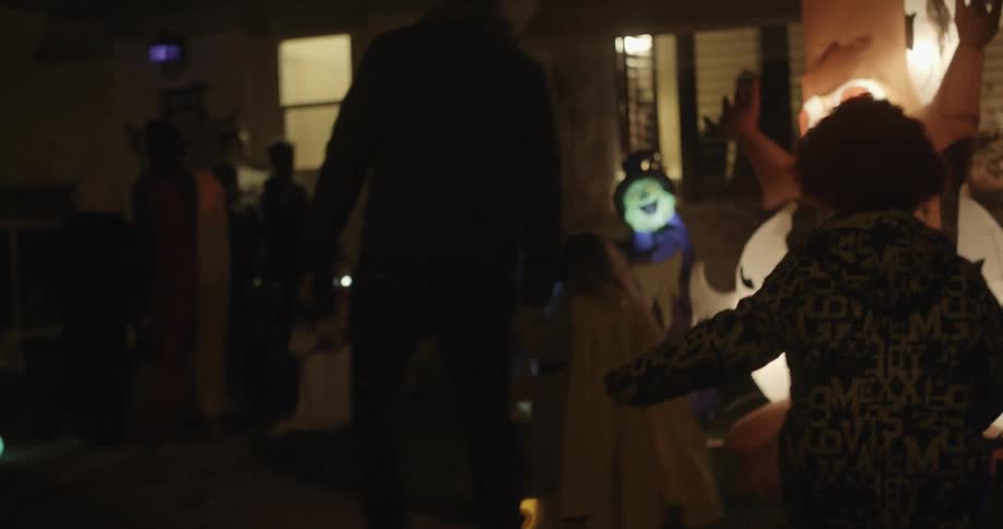 Two young children are walked to a door to trick or treat