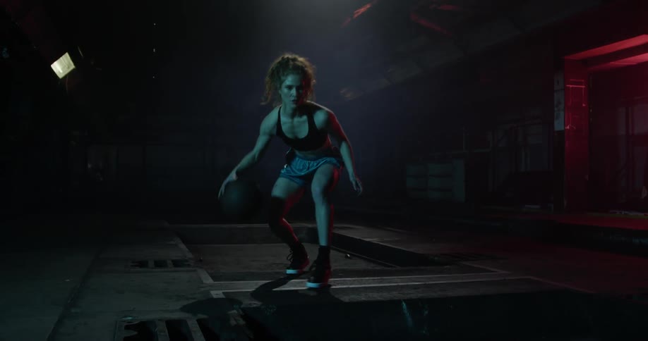A woman dribbles a basketball between her legs