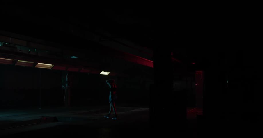 A woman walks around a dimly lit gym